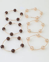 The six wire bangles laid flat: three leopard bead and three gold bead