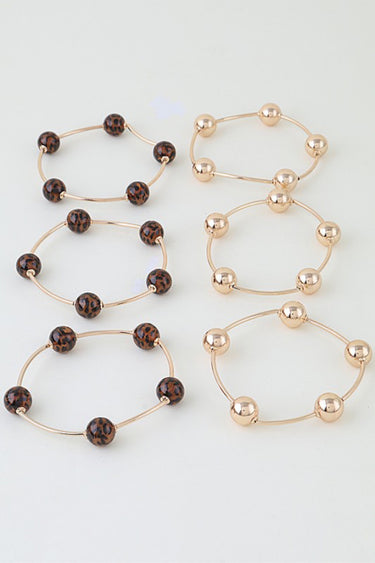The six wire bangles laid flat: three leopard bead and three gold bead