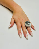 Close‑up of silver statement ring showing polished finish and flowing form