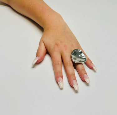 Close‑up of silver statement ring showing polished finish and flowing form