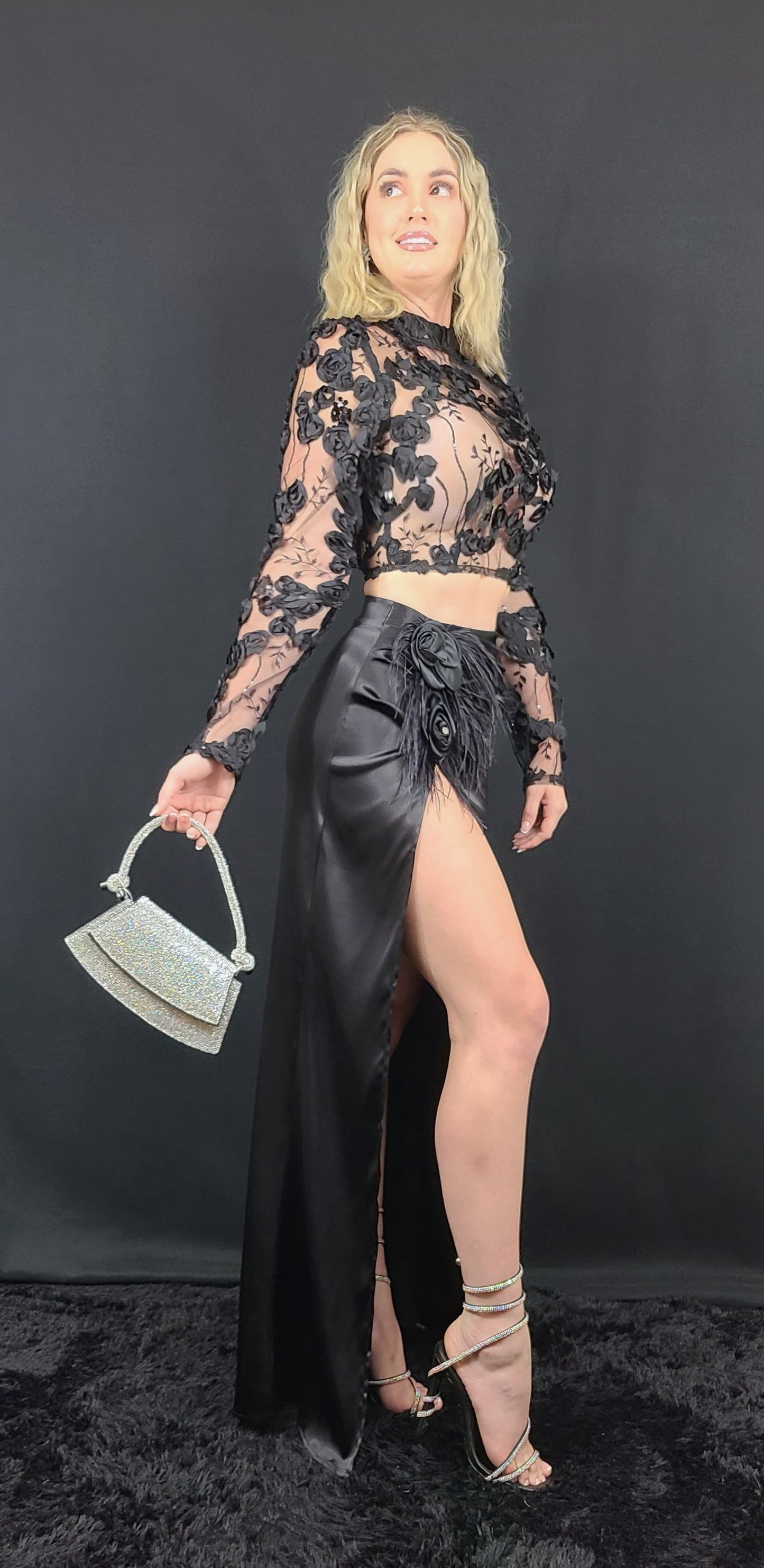 Sheer lace floral top with long sleeves and a sleek black satin skirt, complete with a floral accent.