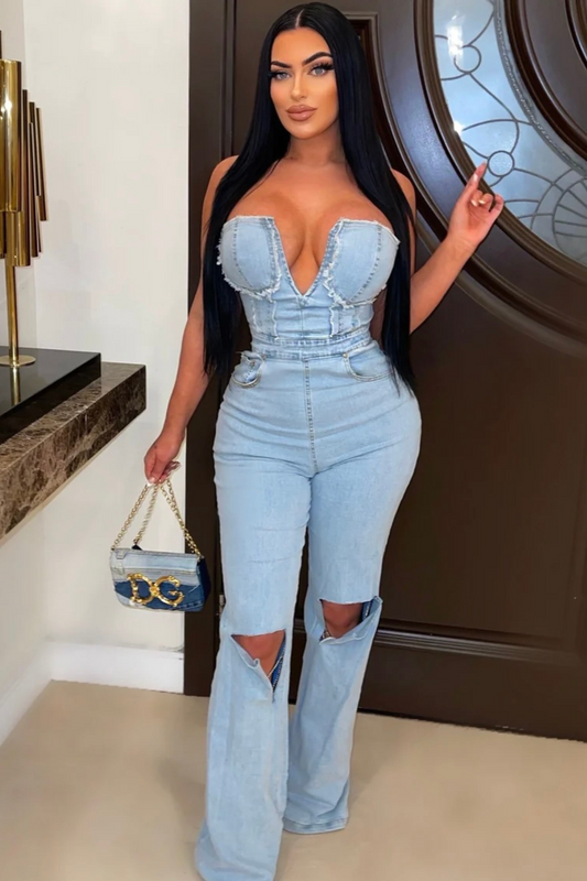 light blue denim jumpsuit with a deep V-neckline and cutout knees, holding a mini denim handbag