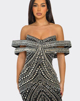 Model posing in sparkly black off-shoulder mini dress