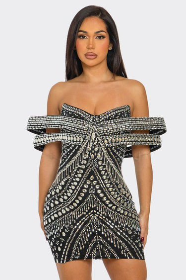 Model posing in sparkly black off-shoulder mini dress