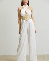 Woman in white embellished halter jumpsuit with gold waist detail