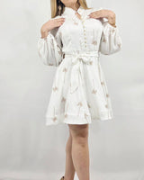 White mini dress with long puff sleeves, a collared neckline, and a belted waist featuring palm tree embroidery.