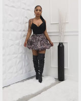 Front view of leopard print bubble mini skirt styled with black top and thigh-high boots

