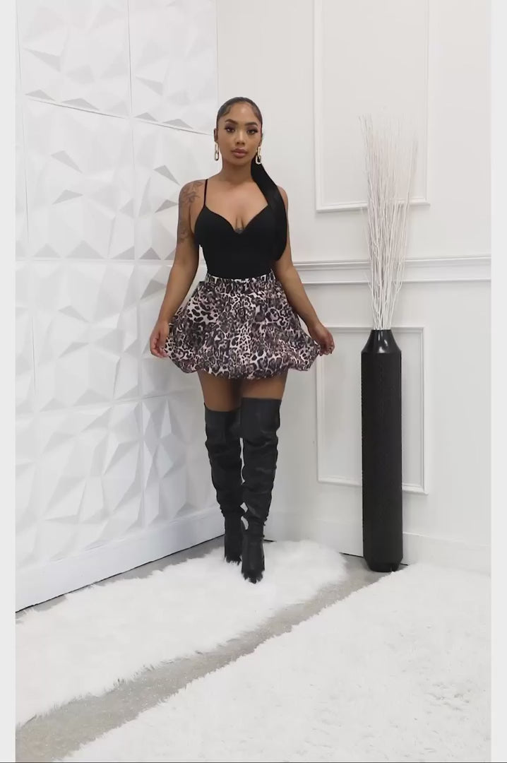 Front view of leopard print bubble mini skirt styled with black top and thigh-high boots
