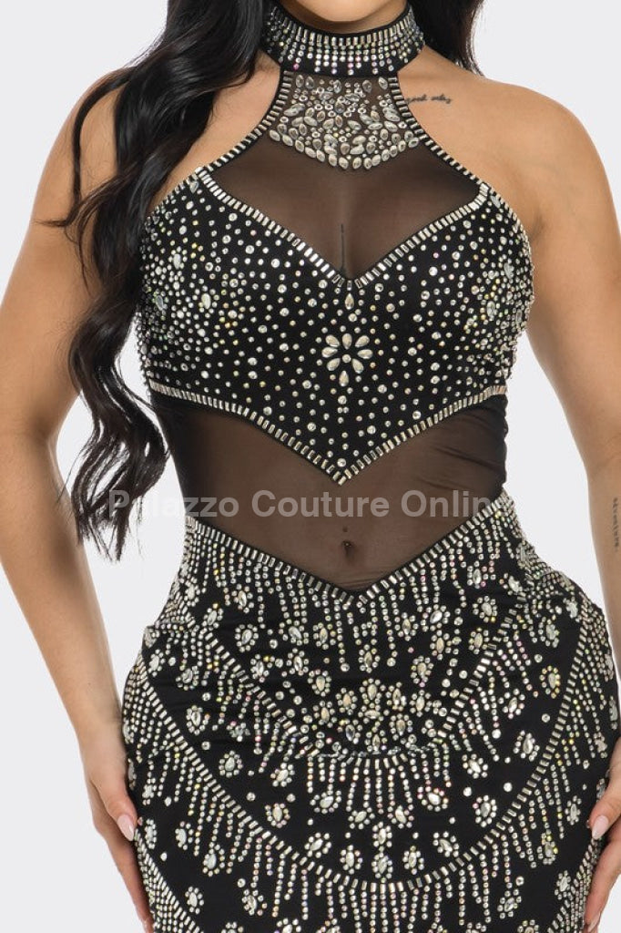 Black evening dress adorned with dazzling rhinestones and a sheer mesh neckline.
