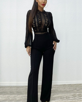 Elegant black jumpsuit with intricate lace detailing on the bodice, sheer sleeves, and a flattering wide-leg silhouette.